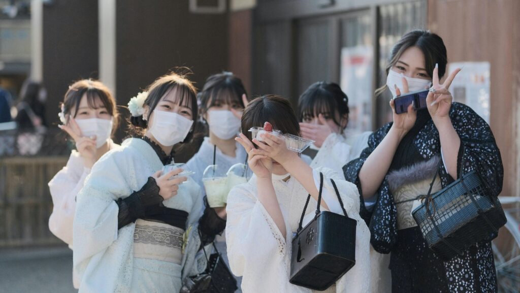 Group of women in traditional yukatas and face masks posing for a photo outdoors.